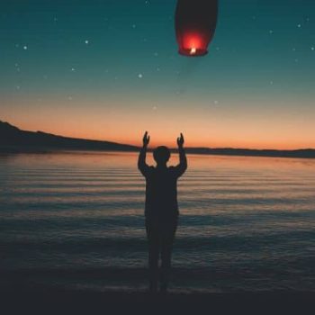 A person holding a kite in the water at night.